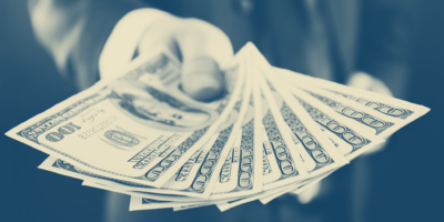 lump-sum investing concept image, hand holding multiple $100 dollar bills in one lump sum